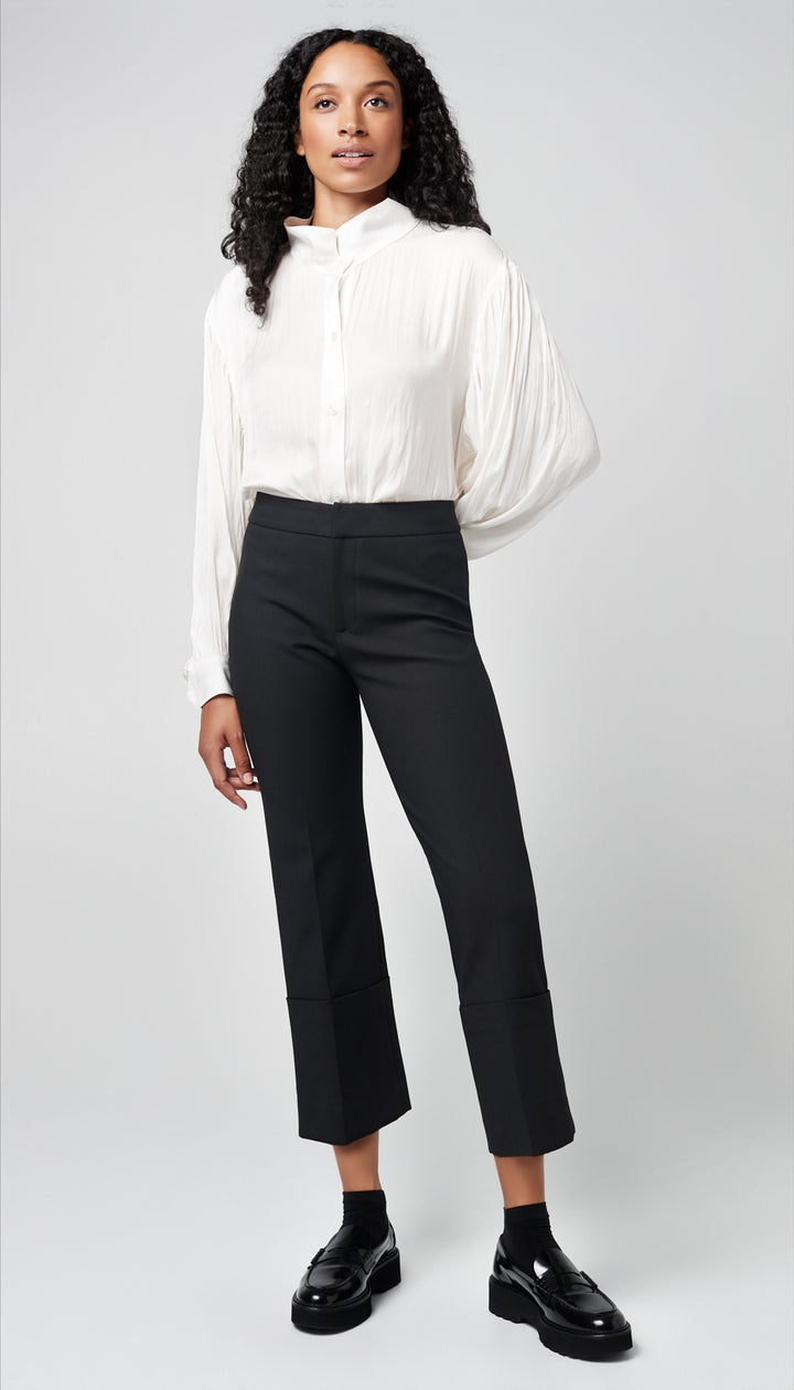 A woman in a solid black cuffed pant and white blouse.
