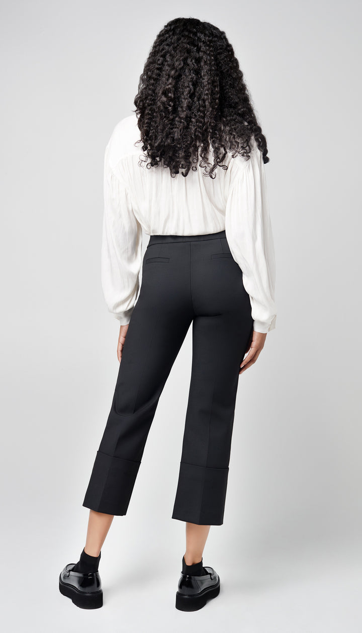 The back of a woman in a solid black pant and white blouse.