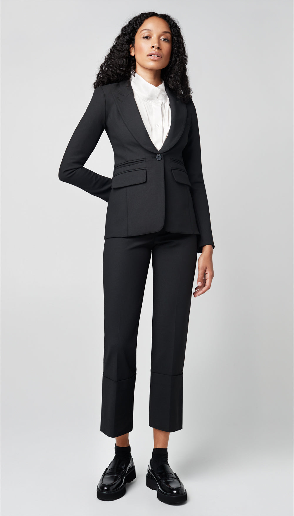 A woman in a solid black blazer and cuffed pant.