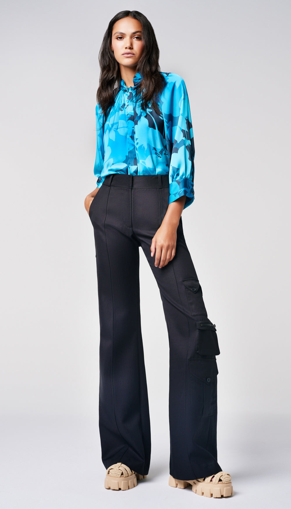 A woman in a blue floral blouse and black cargo pants.