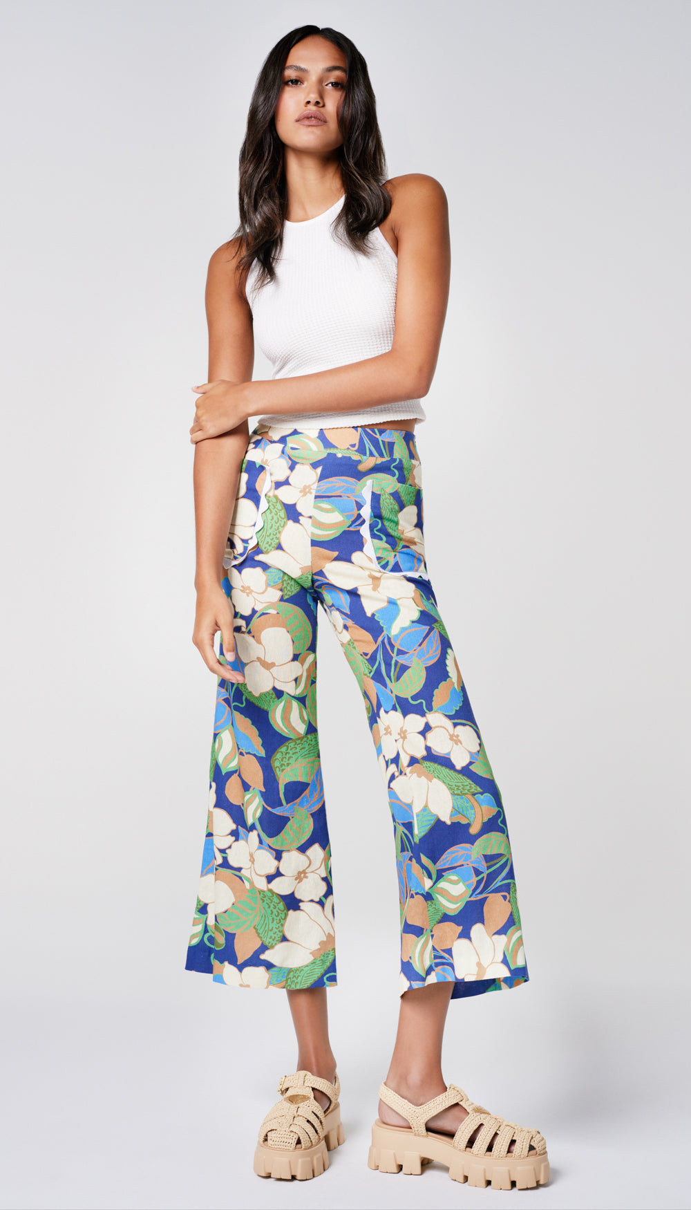 A woman in a blue floral pant and white tank.
