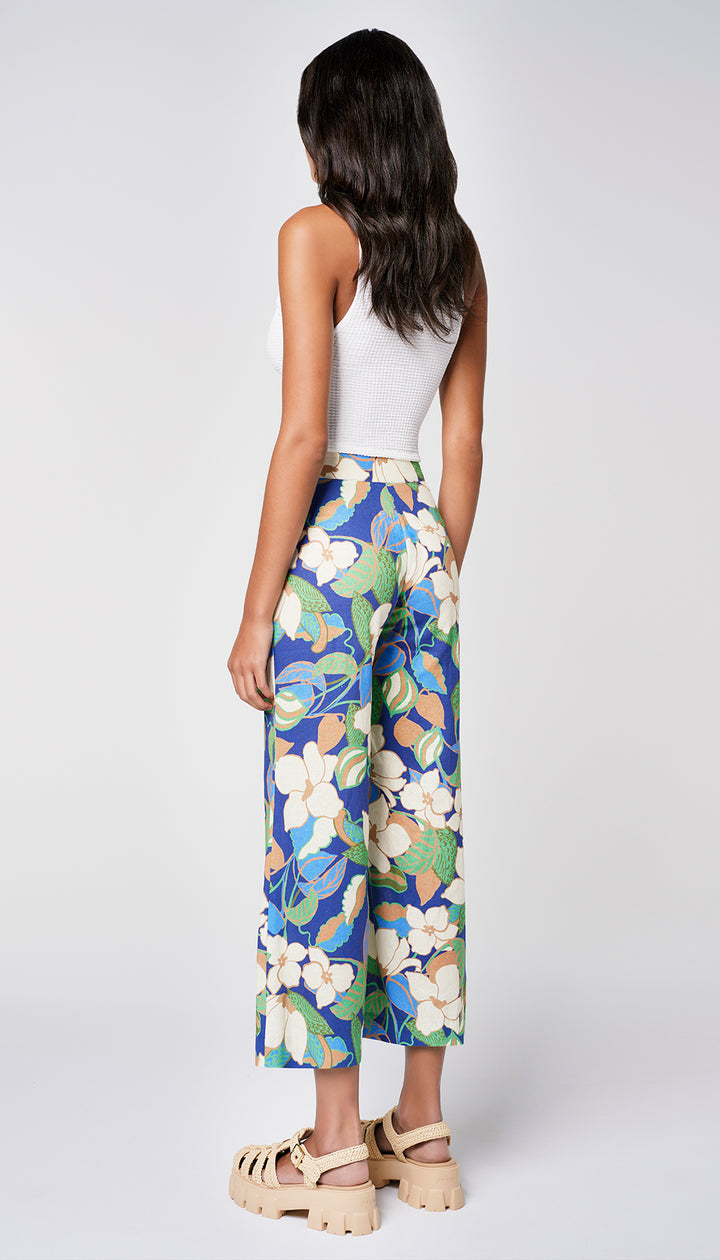 The back of a woman in a blue floral pant and white tank.