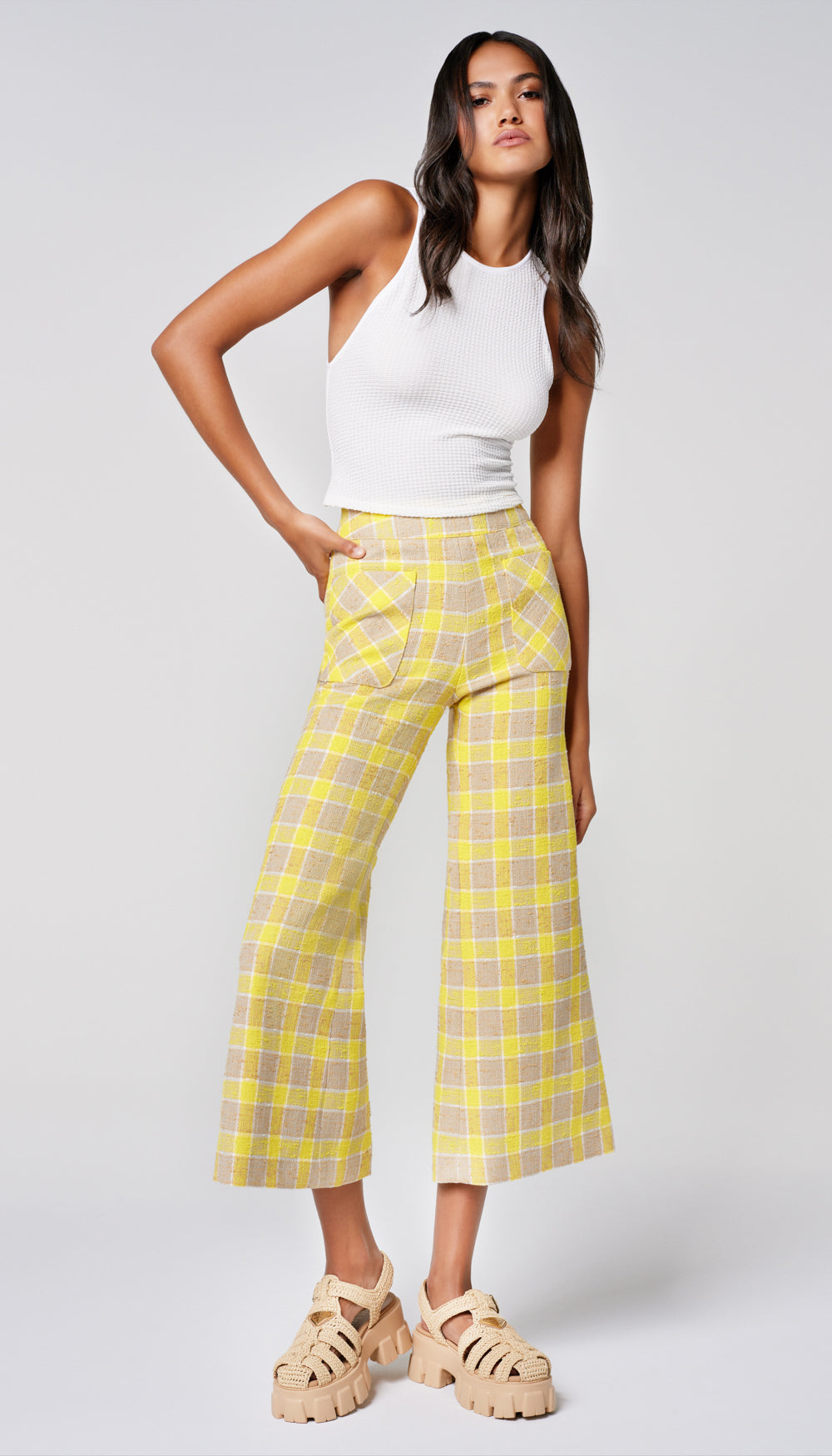 A woman in a yellow check pant and white tank.