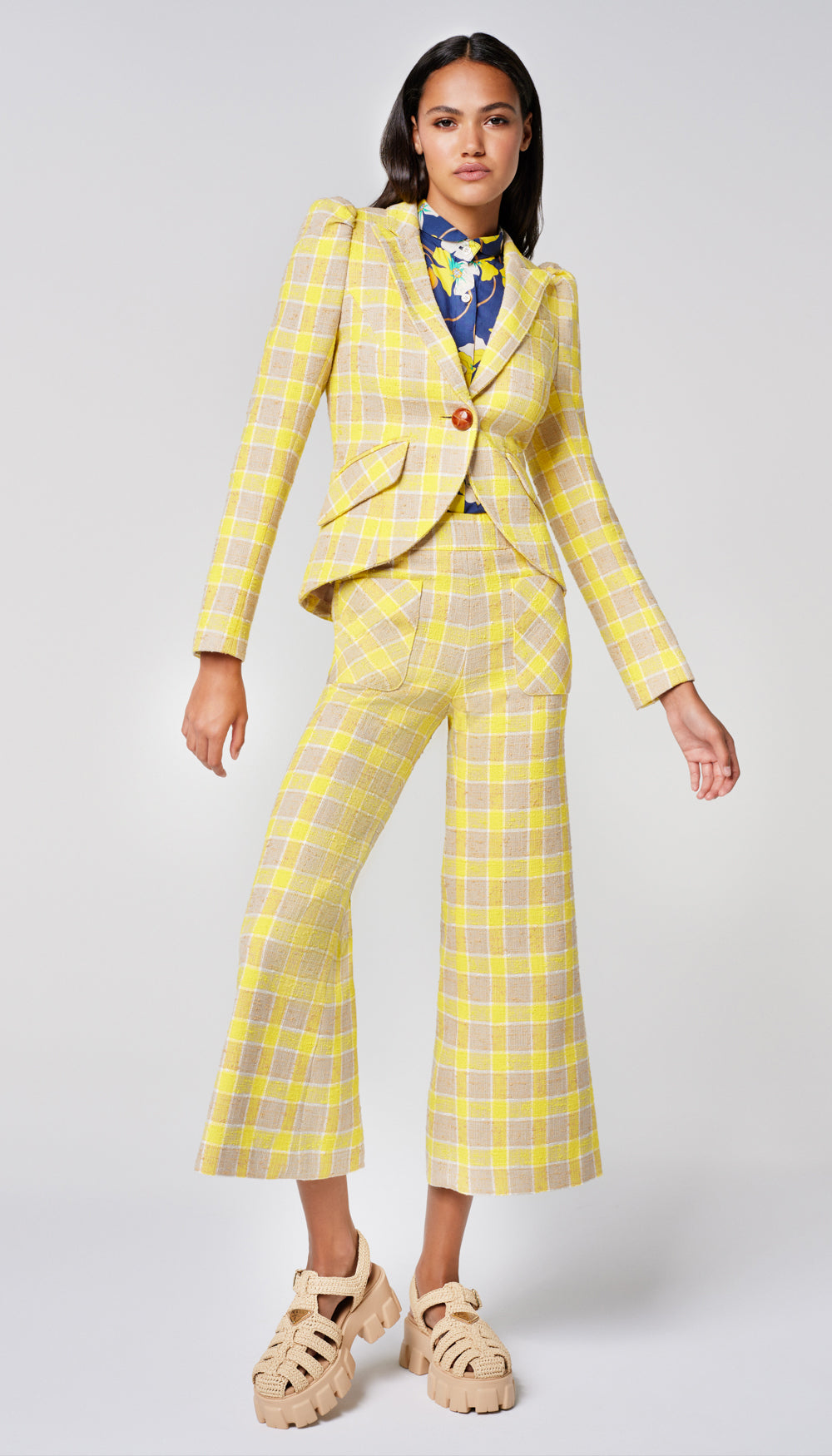 A woman in a yellow check blazer and cropped pant.