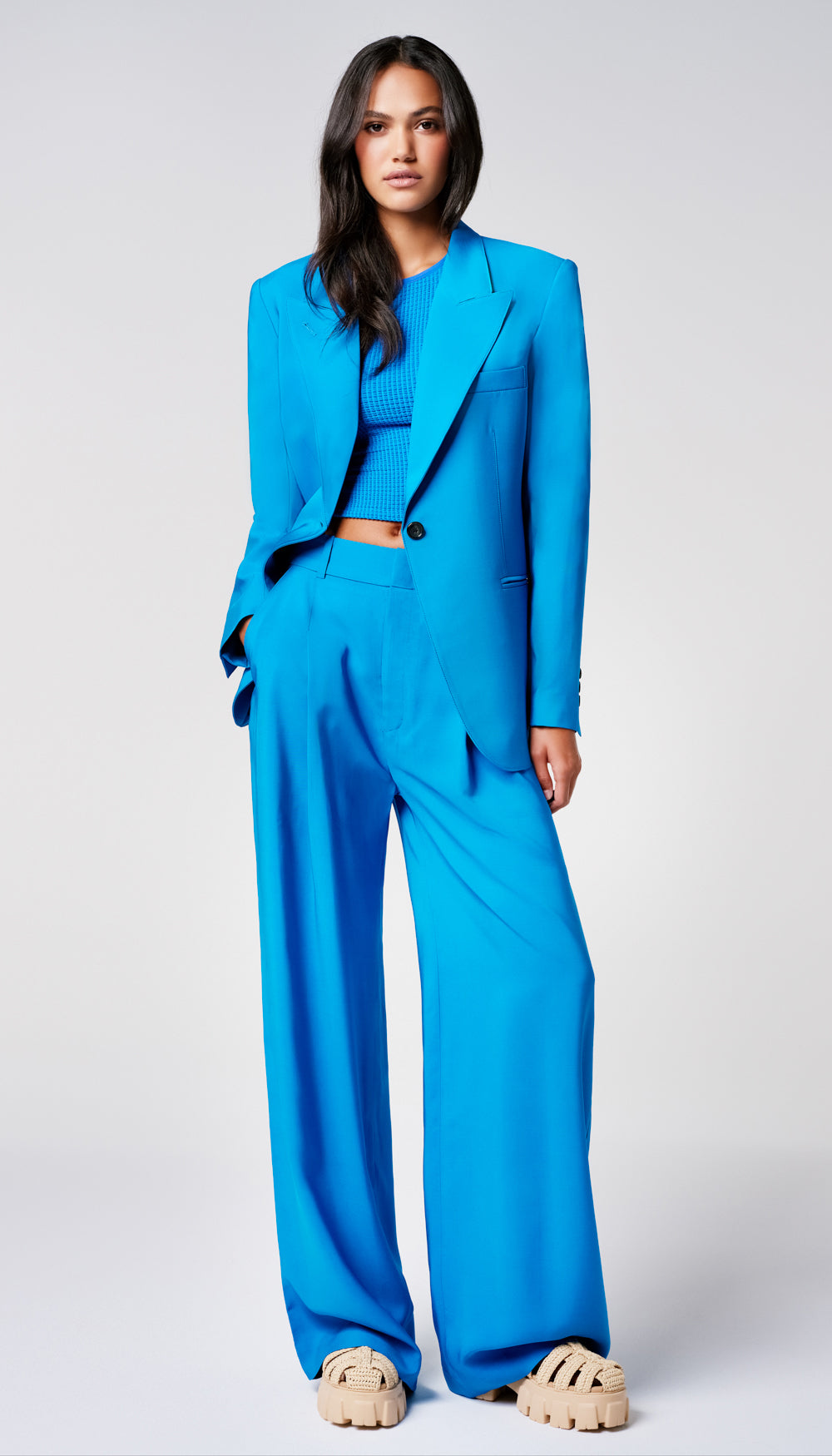 A woman in an oversized blue blazer and wide leg trousers.