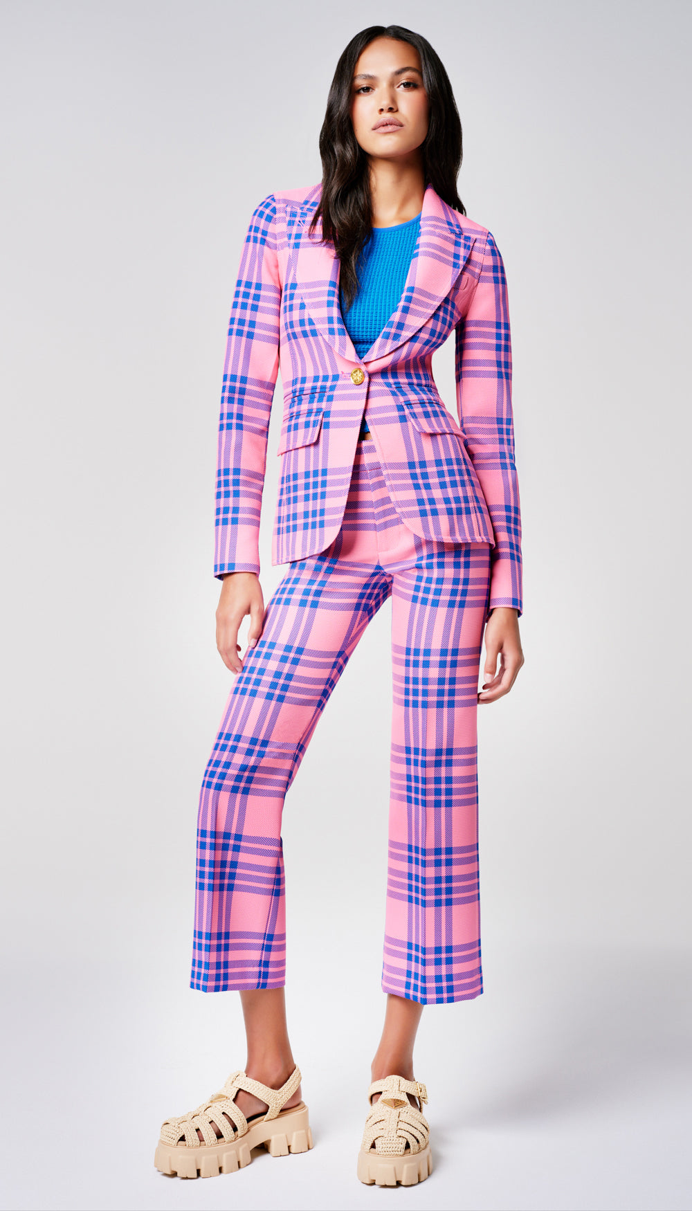 A woman in a pink and blue plaid blazer and pant.