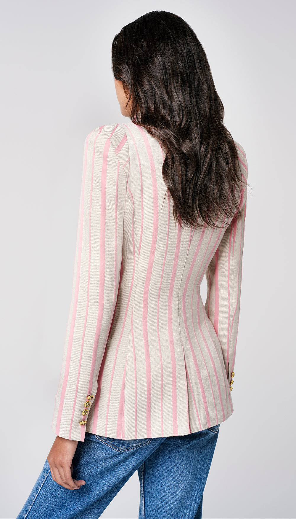 The back of a woman in a stone and rose stripe blazer.