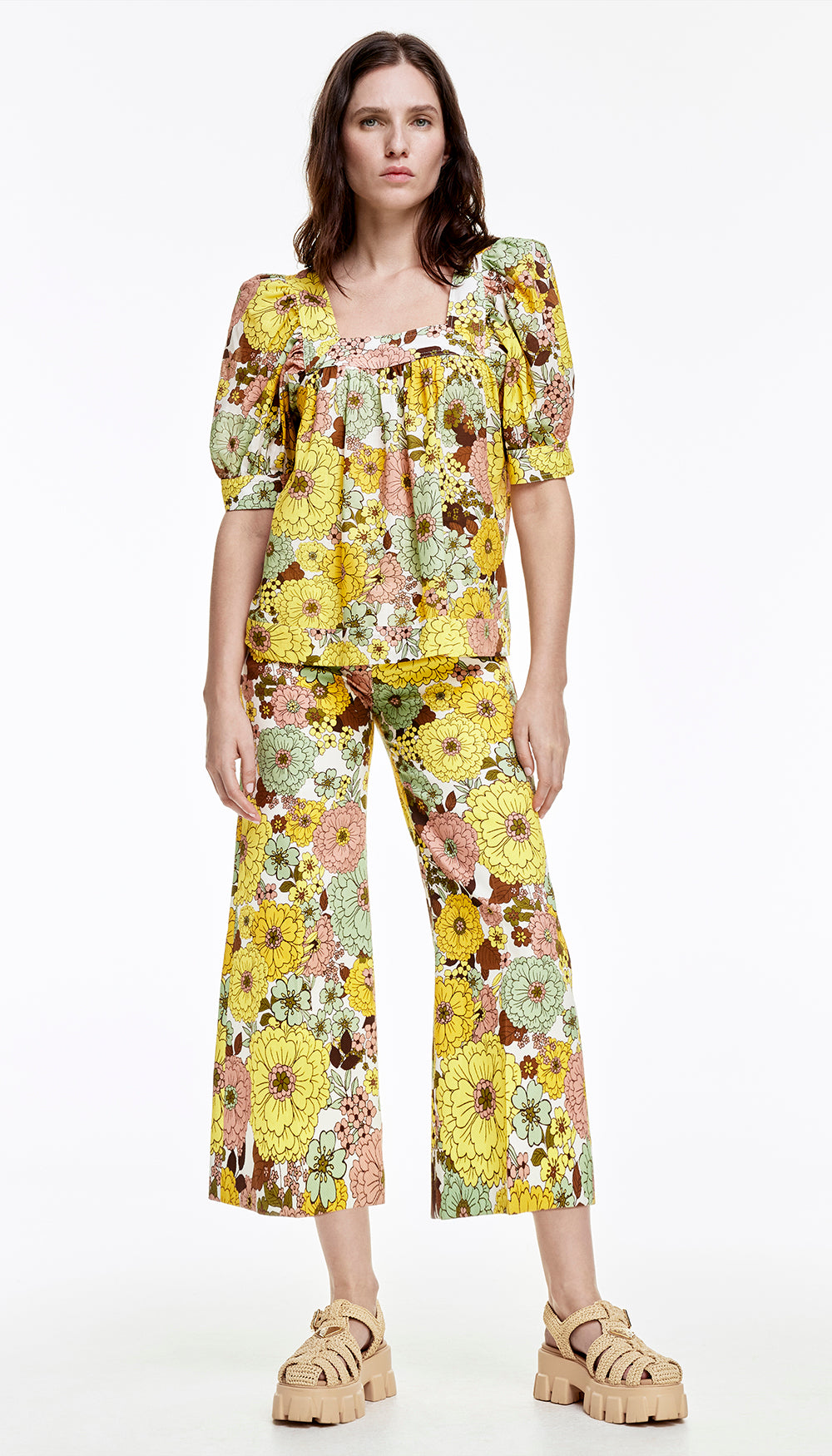 A woman in a yellow floral print blouse and pant.